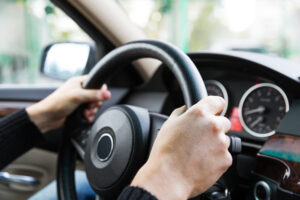 Close up of man hands driving a car during sunlight